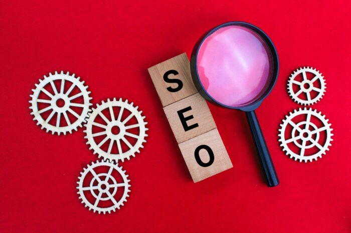 magnifying glass and gear teeth with the letters SEO or the word Search Engine Optimization